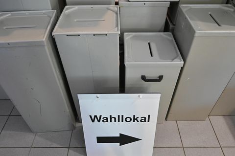 Leere Wahlurnen, davor ein Schild mit der Aufschrift Wahllokal und einem Pfeil nach rechts