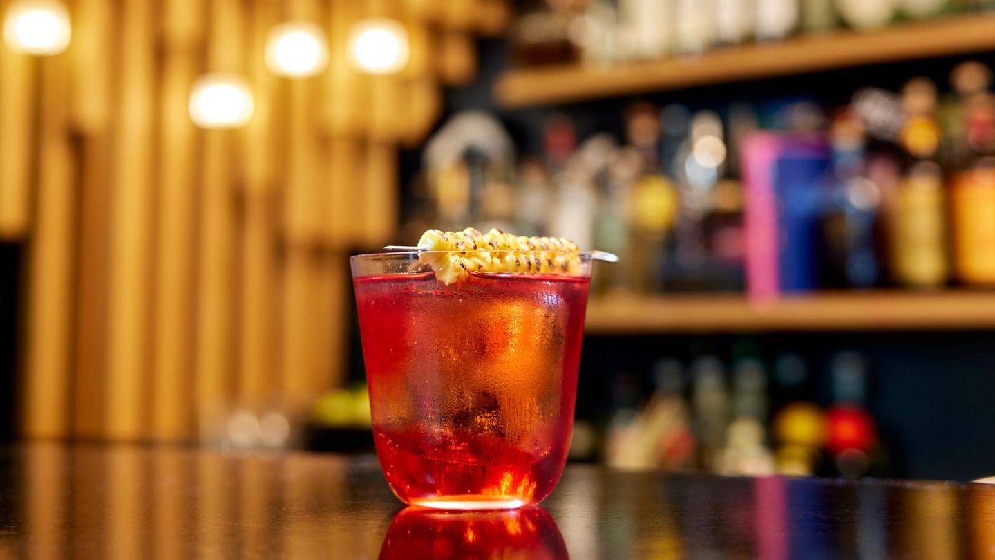Drink: Cornstar Negroni  München: Trisoux Bar  Bartender: Philipp Fröhlich     Rezept:  3cl Campari  3cl Mezcal (Montelobos)  2cl Amontillado Sherry  1,5cl Nixta Mais Likör  Garnitur: Burnt Corn Rib (abgeflammter / gegrillter Mais)     Zubereitung:  Auf Eis für ca. 15 Sekunden kalt rühren. In ein vorgekühltes Glas auf Eis abseihen.  Inspiration: "Der Drink ist von unseren Reisen nach Mexiko, insbesondere Oaxaca, inspiriert. Auf den lebhaften Märkten der Hauptstadt des gleichnamigen Bundesstaats liegt stets ein Geruch von Gewürzen, Rauch und eben Mais, als Hauptzutat der mexikanischen Küche in der Luft."