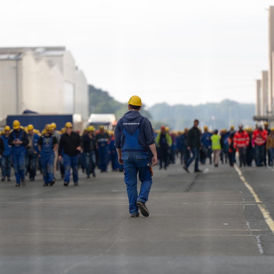 Mitarbeiter der Meyer Werft laufen über das Firmengelände