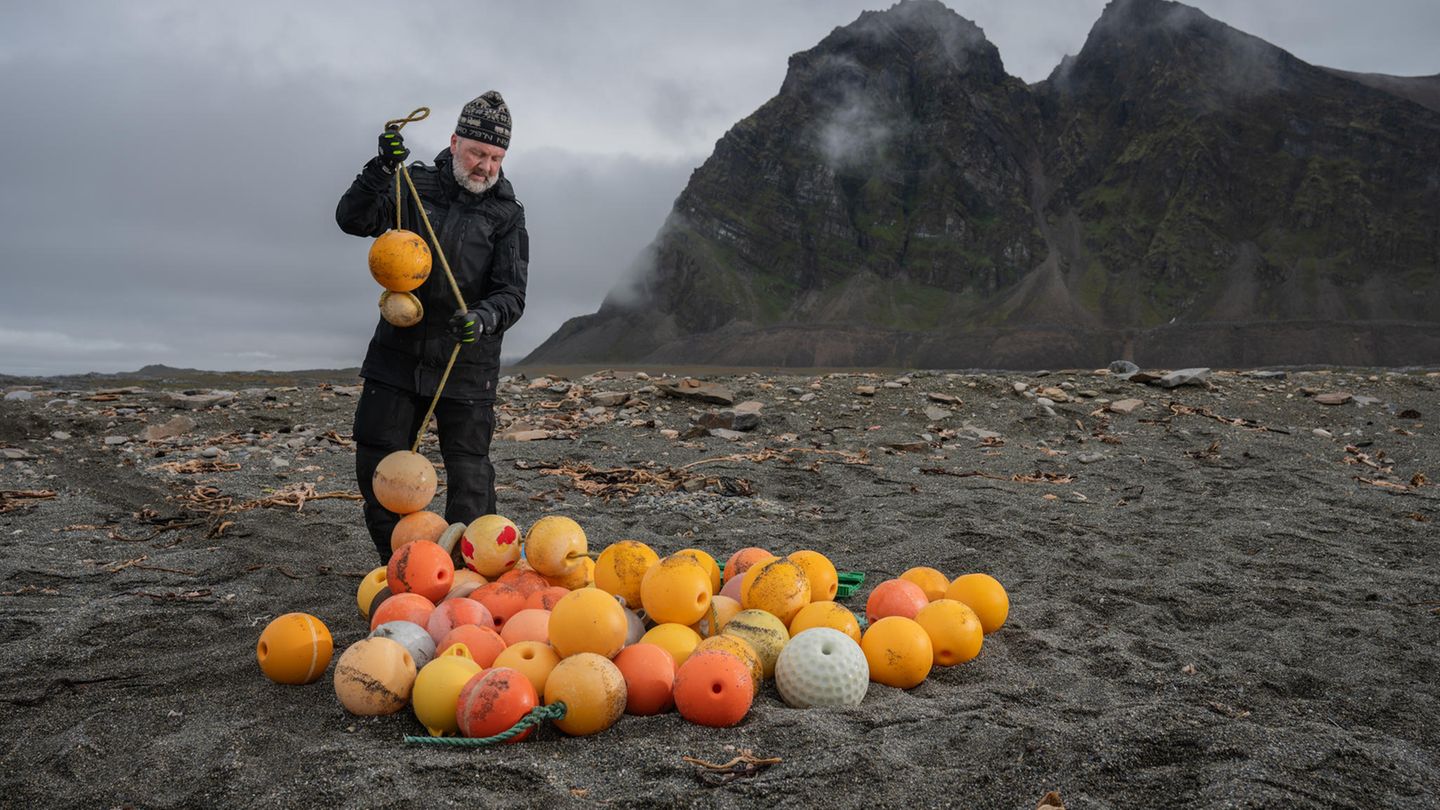 Nachhaltigkeit: Ein Müllsammler sammelt orange Bojen am Strand ein