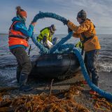 Nachhaltigkeit: Zwei Helfer laden ein angeschwemmtes Schiffstau auf ein Schlauchboot