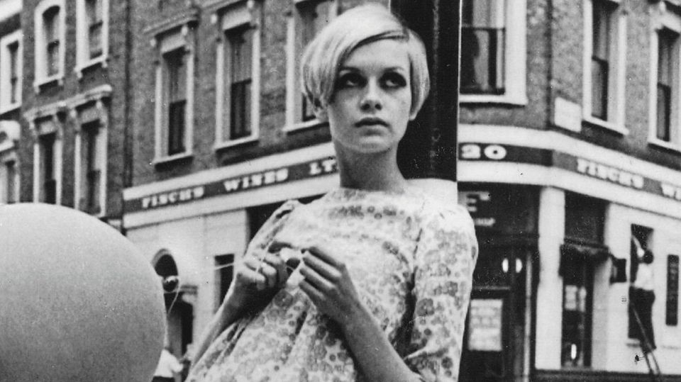 Twiggy in schwarz-weiß, wie sie an einem Laternenpfahl lehnt