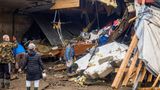 Menschen blicken auf Trümmer von Häusern