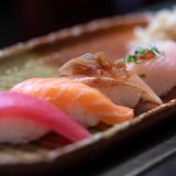 Sushi entstand ursprünglich im Südosten Asiens als Methode, um Fisch zu konservieren, indem man ihn in fermentiertem Reis einlegte. Die Verbreitung in Japan im 8. Jahrhundert führte zur Entwicklung des modernen Sushi, bei dem frischer Fisch und Essigreis verwendet werden. Es wird in verschiedenen Formen serviert, darunter "Maki", in Seetang gerollt, und "Nigiri", Fisch auf Reis. Es wird üblicherweise mit Sojasauce, eingelegtem Ingwer und Wasabi serviert.