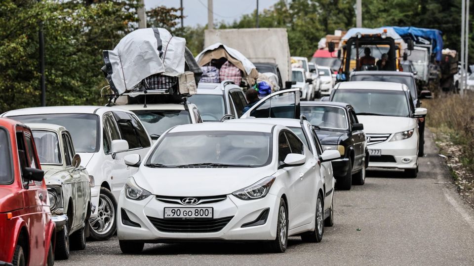 Fahrzeuge aus Bergkarabach stehen eng hintereinander auf einer Straße Richtung Armenien