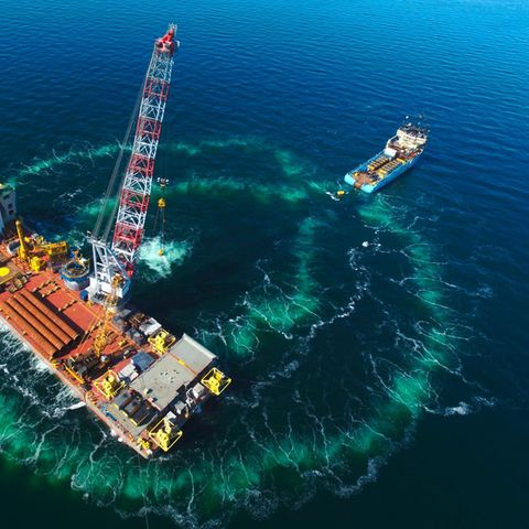 Beim Bau des Windparks "Hohe See" rammt ein Technikschiff (vorn) die Fundamente für Windrotoren in den Meeresgrund.