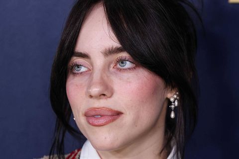 Billie Eilish mit hochgesteckten Haaren vor lila Hintergrund