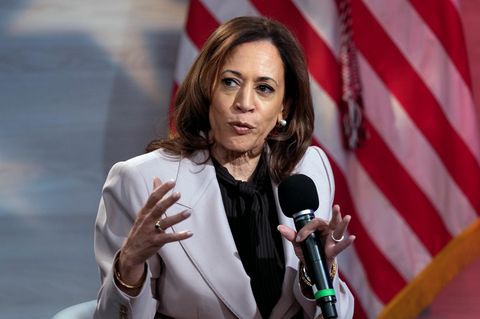 Kamala Harris spricht und gestikuliert vor einer Flagge der USA