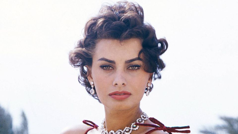 Sophia Loren in rotem Kleid, mit Edelsteinkette, blickt in die Kamera