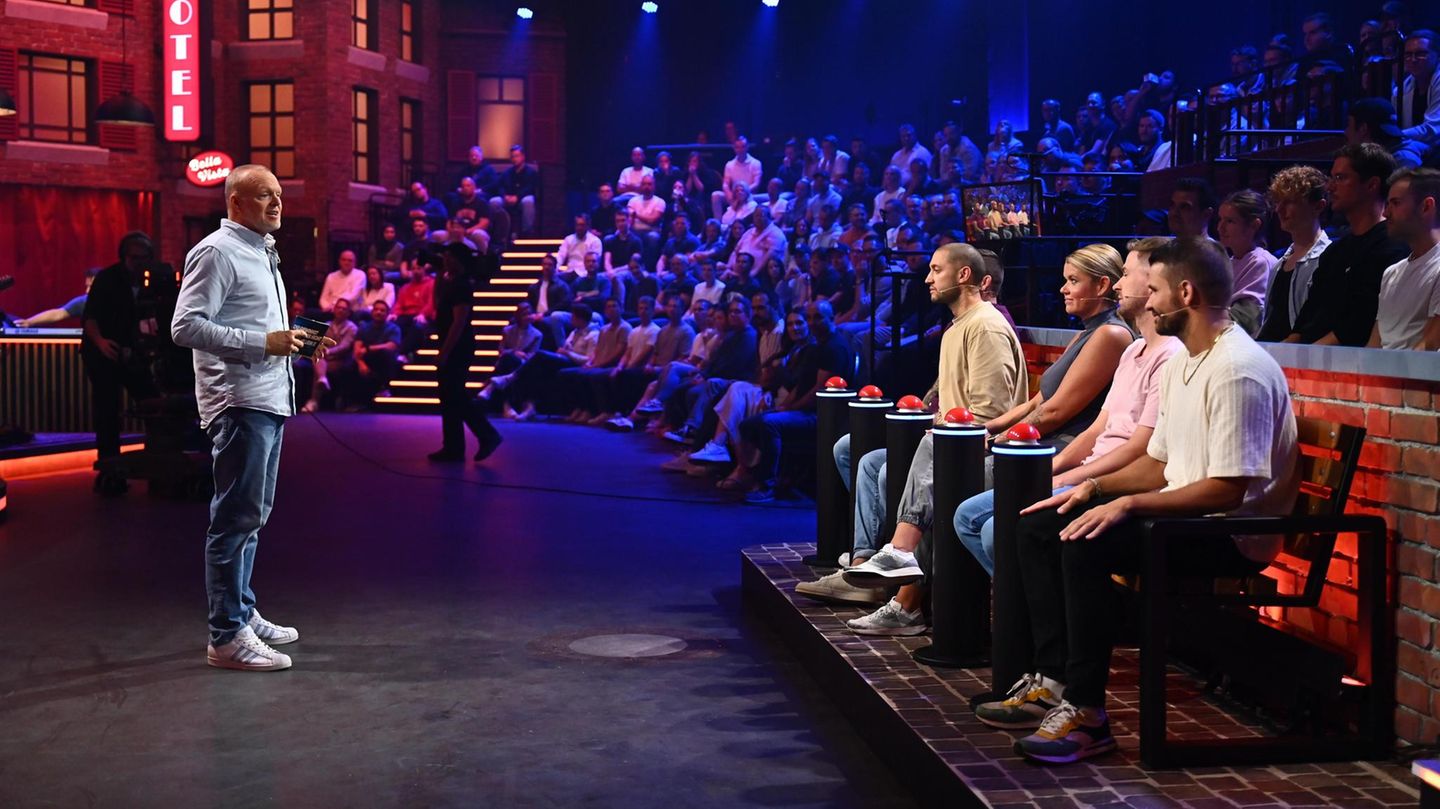 Stefan Raab steht vor vier Kandidaten, die jeweils einen roten Buzzer vor sich haben