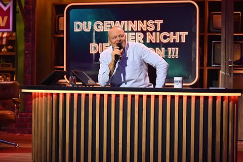 Der Moderator Stefan Raab sitzt am Pult seiner neuen Show beim Streaminganbieter RTL Plus, er trägt ein blaues Hemd