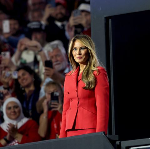 Melania Trump steht im roten Kostüm bei einem Auftritt