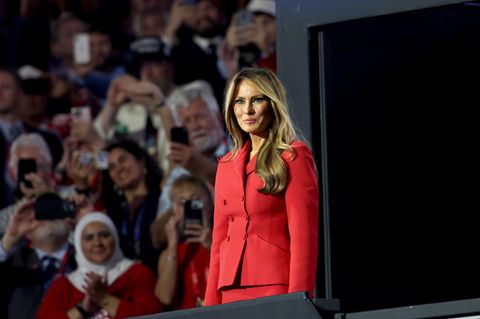 Melania Trump steht im roten Kostüm bei einem Auftritt