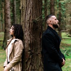 Trennungsgründe: Paar steht Rücken an Rücken an einen Baum gelehnt