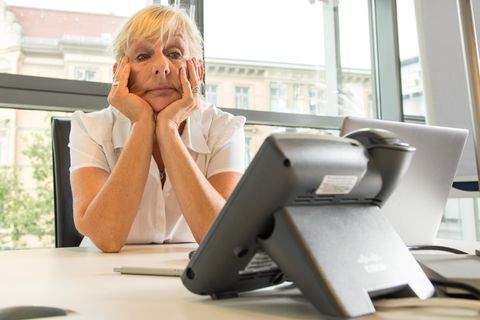 Symbolbild Rente: Frau sitzt gefrustet auf der Arbeit