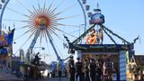 Polizisten stehen an einem Stand, dahinter kann man ein Riesenrad sehen