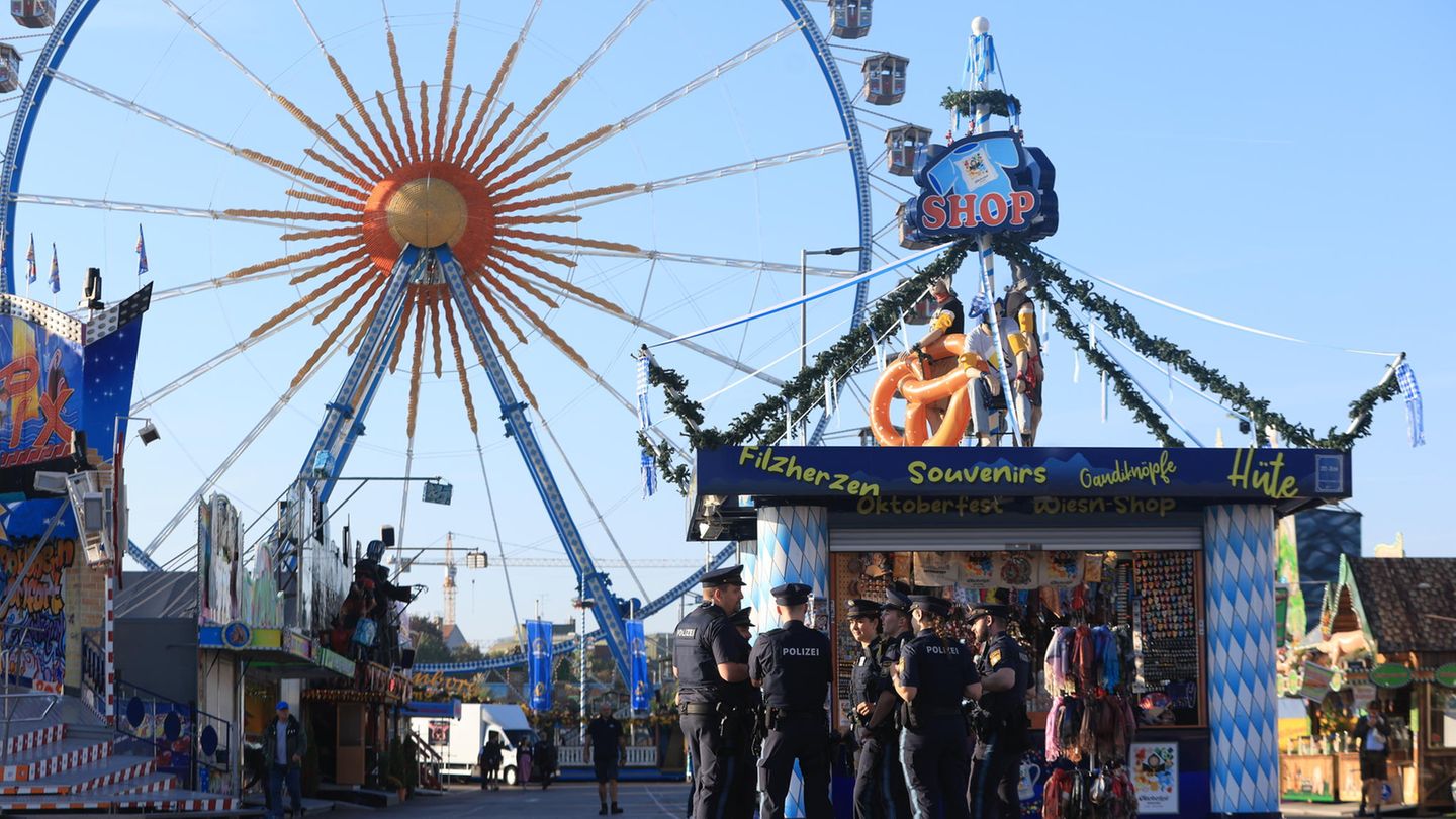 Polizisten stehen an einem Stand, dahinter kann man ein Riesenrad sehen