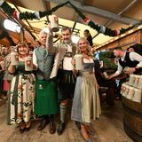 Petra und Dieter Reiter stehen links, Markus Söder und Karin Baumüller-Söder rechts nach dem Anstich und prosten zu