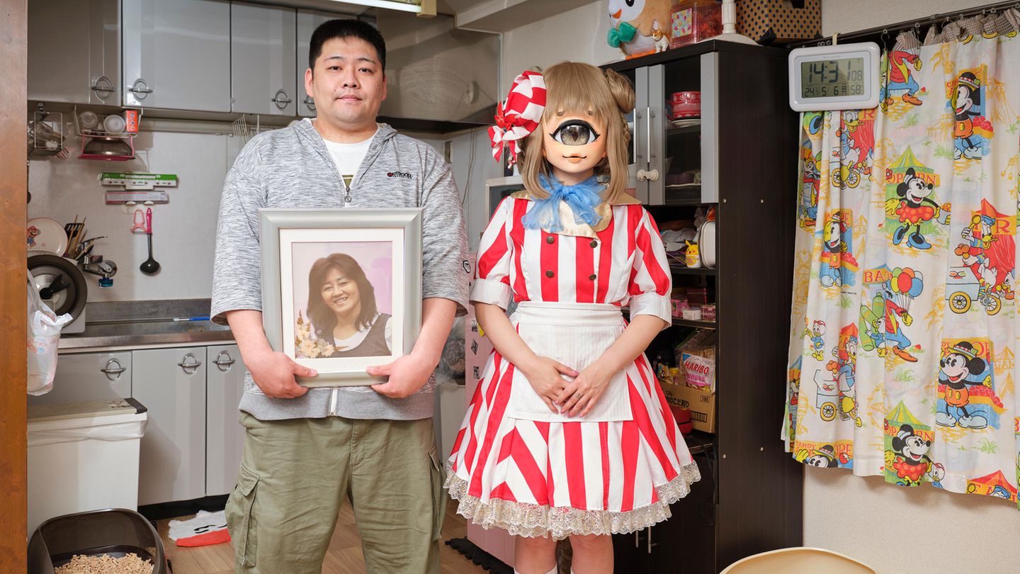 Cosplayerin Monaka posiert mit ihrem Bruder der ein Foto der verstorbenen Mutter in der Hand hält in ihrem Kostüm in der Küche