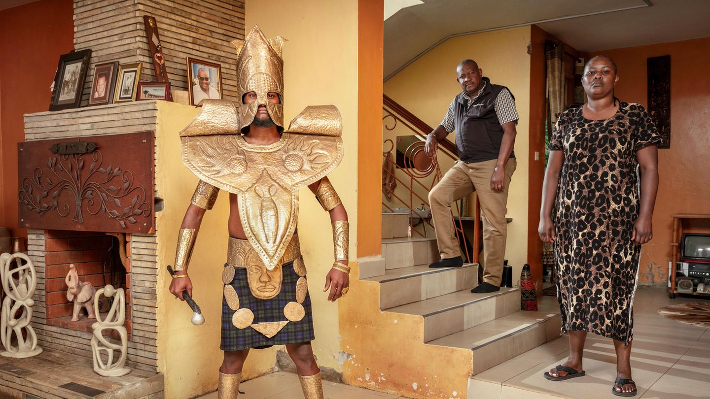 Cosplayer Nicky posiert als "God of Iron" mit seinem Onkel und seiner Tante im Wohnzimmer