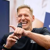 Ralf Moeller spricht in ein Mikrofon und zeigt mit dem Zeigefinger in die Menge