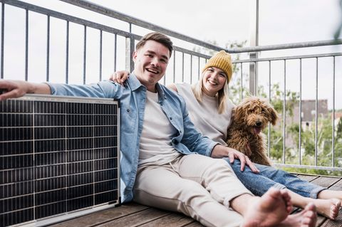 Watt Peak: Junges Paar sitzt mit einem Solarmodul und Hund auf dem Balkon.