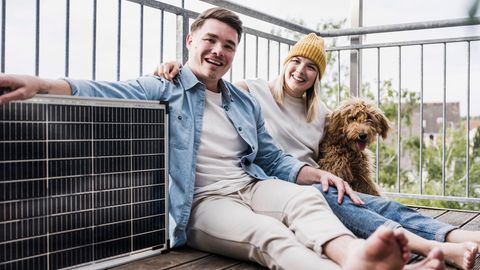 Watt Peak: Junges Paar sitzt mit einem Solarmodul und Hund auf dem Balkon.