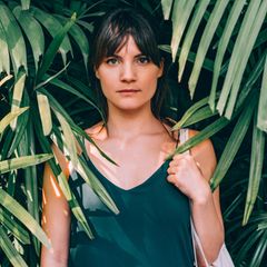 Auswandern: Eine junge Frau steht unter Palmen