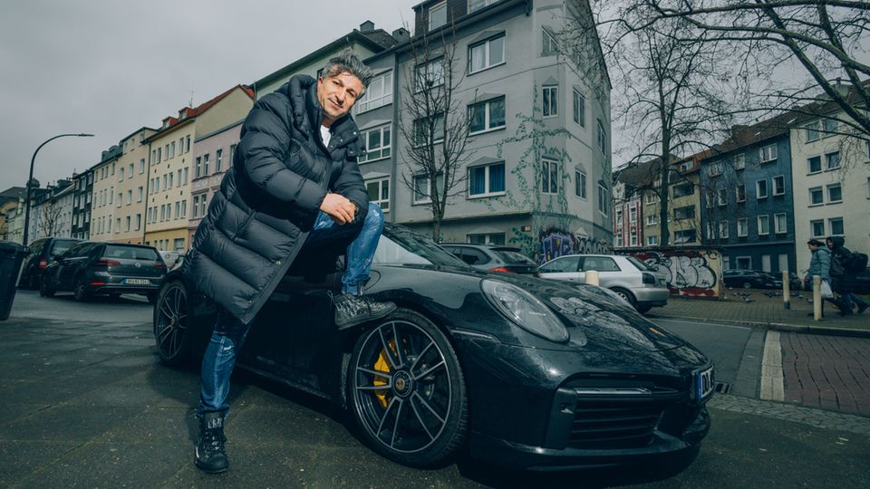 Lottomillionär Chico posiert vor seinem Porsche in Dortmund