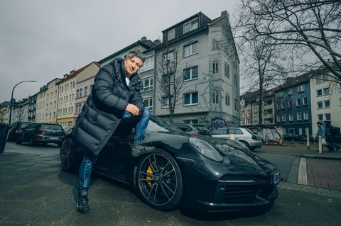 Lottomillionär Chico posiert vor seinem Porsche in Dortmund