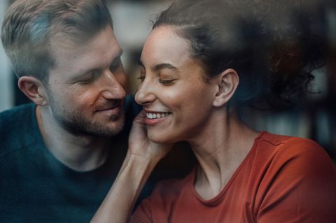 ein Mann flüstert einer Frau etwas ins Ohr