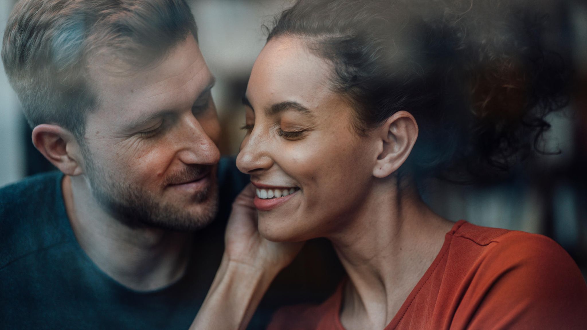 ein Mann flüstert einer Frau etwas ins Ohr