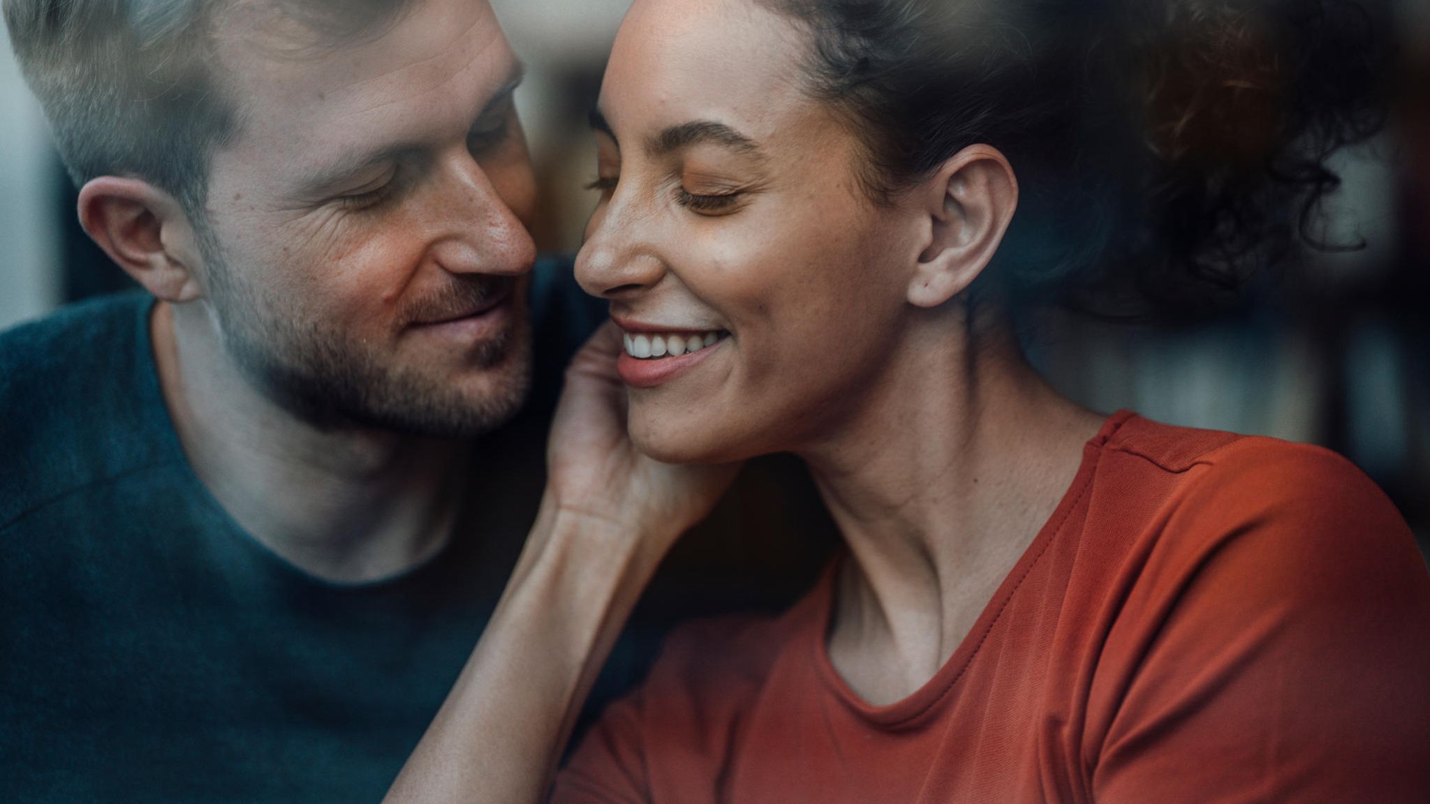 ein Mann flüstert einer Frau etwas ins Ohr