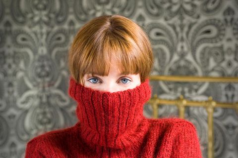 Unsicherheit: Junge Frau hat einen Wollpulli bis zur Nase hochgezogen