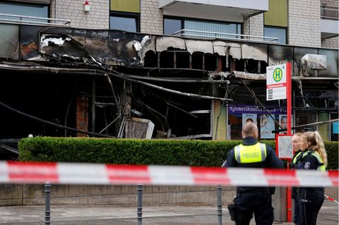 Polizisten vor der verrußten Fassade eines Cafés in Köln nach einer erneuten Explosion