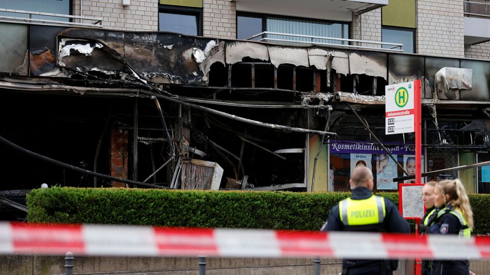 Polizisten vor der verrußten Fassade eines Cafés in Köln nach einer erneuten Explosion