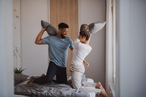 Spiele für Paare: Ein Pärchen hat eine Kissenschlacht auf dem Bett