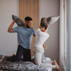 Spiele für Paare: Ein Pärchen hat eine Kissenschlacht auf dem Bett