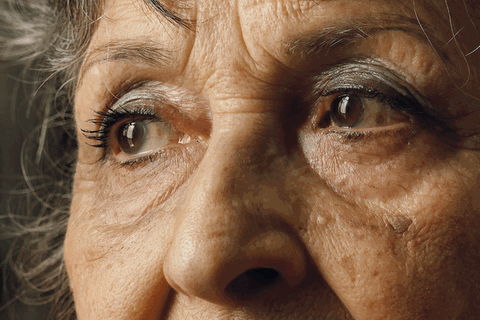 Eine alte Dame, eine Seniorin, schaut und blinzelt