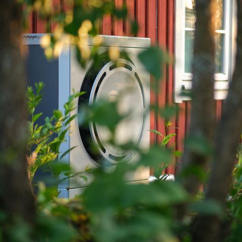 eine Wärmepumpe an der Fassade eines Holzhauses