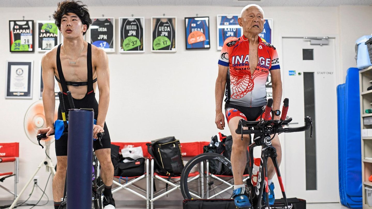 Ein junger und ein alter Mann trainieren nebeneinander auf dem Rad im Fitnessstudio