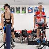 Ein junger und ein alter Mann trainieren nebeneinander auf dem Rad im Fitnessstudio