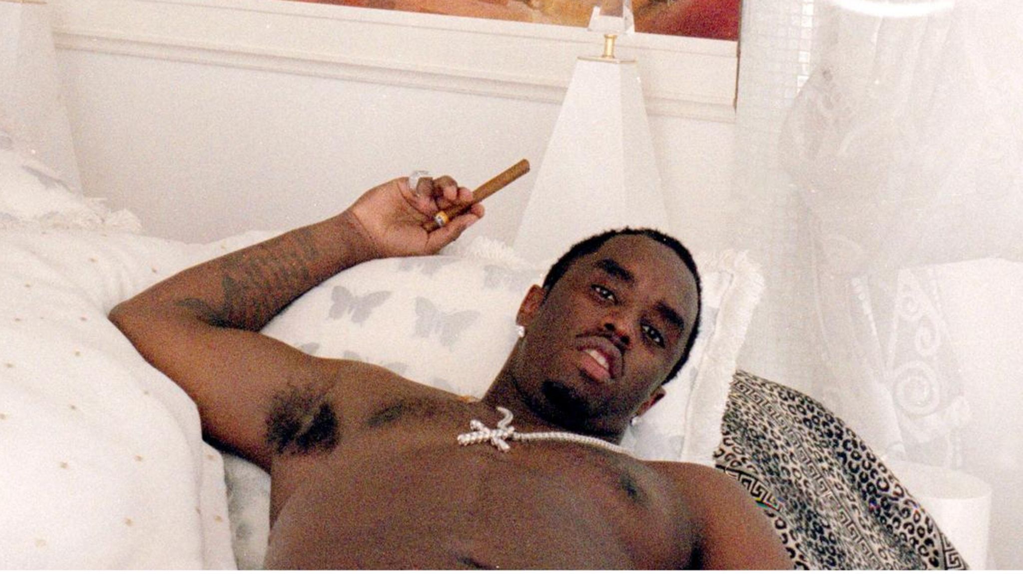P. Diddy in einem Bett mit Zigarre in der Hand und Gemälde über dem Bett