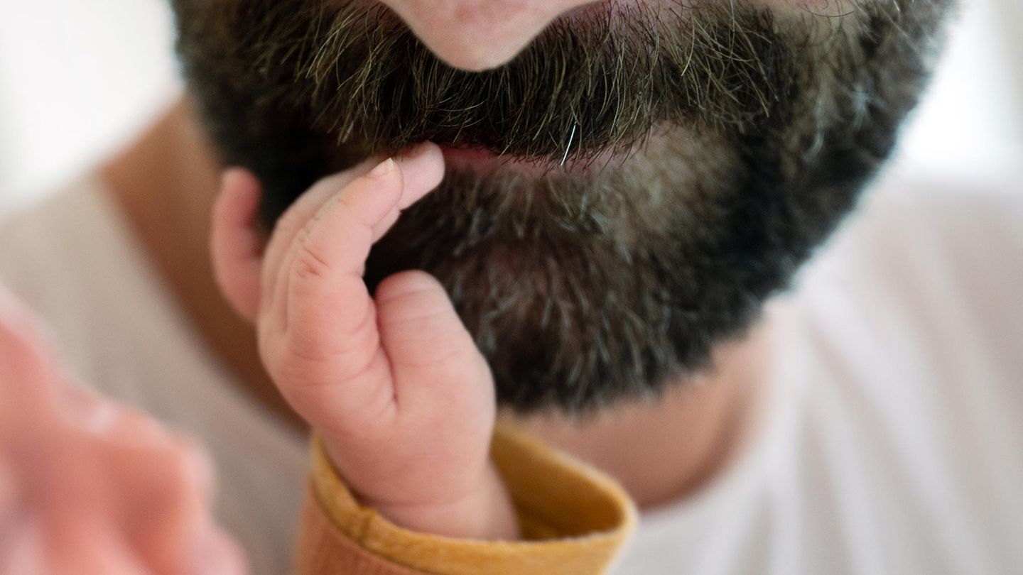 Väterrechte: Eine Babyhand berührt den Mund eines bärtigen Mannes