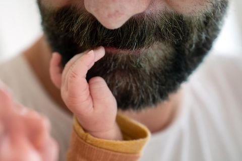 Väterrechte: Eine Babyhand berührt den Mund eines bärtigen Mannes