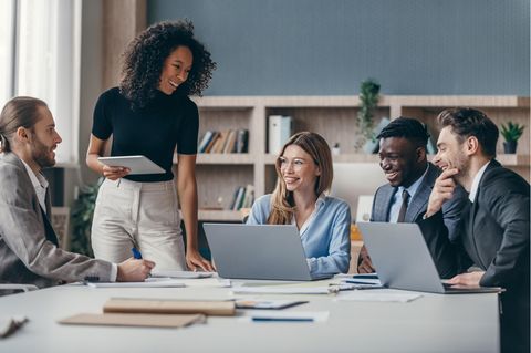 Internet-Tarife für kleine Unternehmen: Menschen in Business-Outfits sitzen vor Laptops an einem Bürotisch.