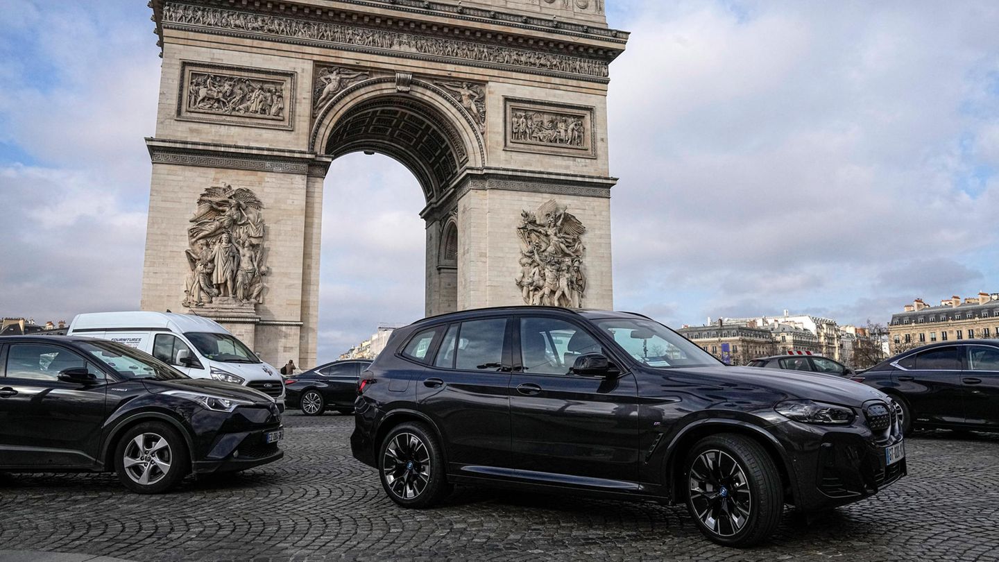 Vor dem Triumphbogen in Paris stehen zwei große Pkw