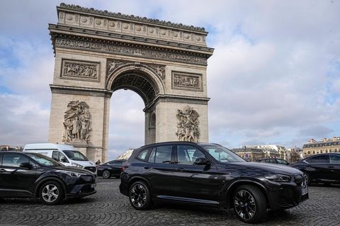 Vor dem Triumphbogen in Paris stehen zwei große Pkw