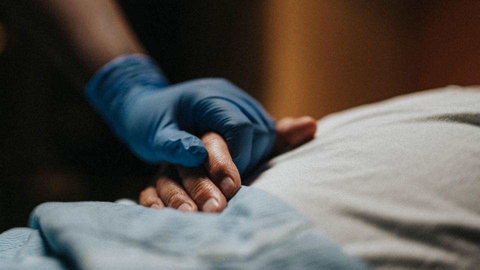 Eine Hand hält die Hand eines Patienten – Pflege statt Suizid wird hier illustriert