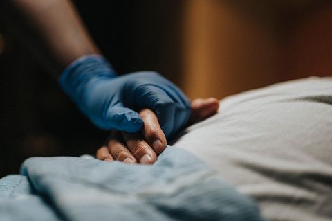 Eine Hand hält die Hand eines Patienten – Pflege statt Suizid wird hier illustriert